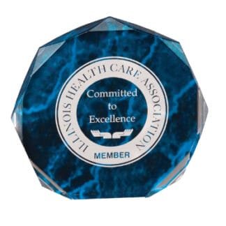 Circular membership badge on a blue marble background, reading 'Illinois Health Care Association' around the edge and 'Committed to Excellence' in the center with a small 'Member' label at the bottom.