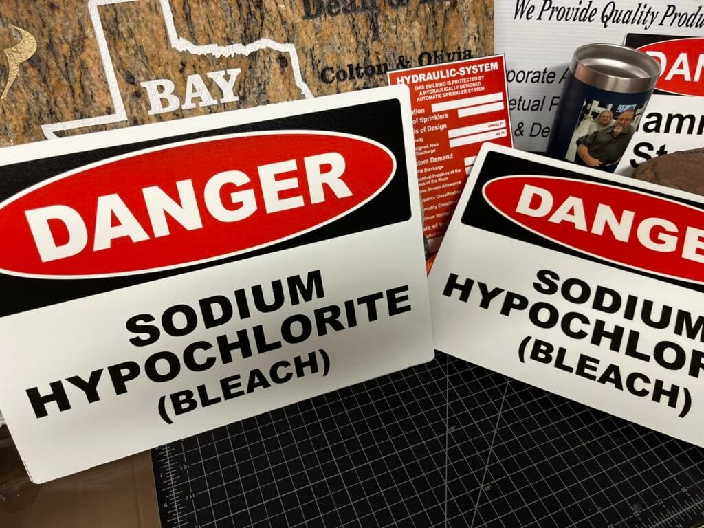 Close-up of overlapping red'DANGER' warning signs with bold white text on a white background, arranged in a collage on a work surface.