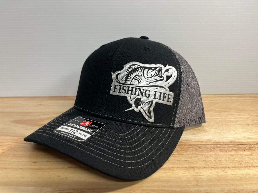 Black trucker cap with a silver fish graphic and the words 'FISHING LIFE' on the front panel.