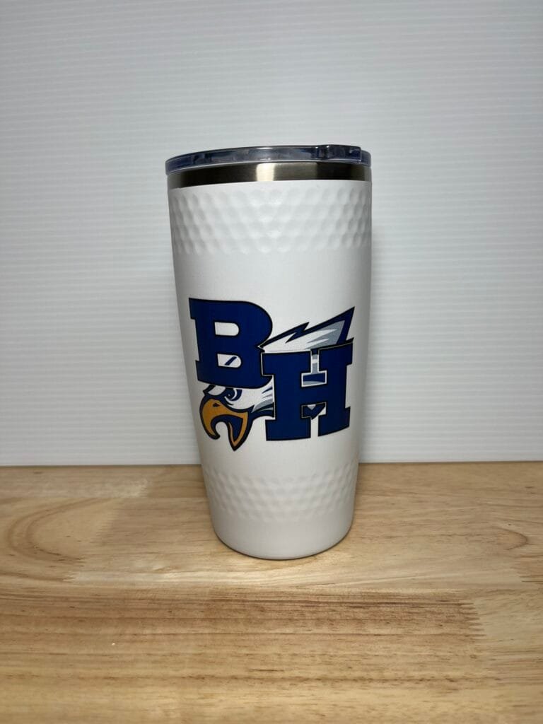 White travel tumbler with blue lid and a bold blue logo on the side, resting on a wooden table.