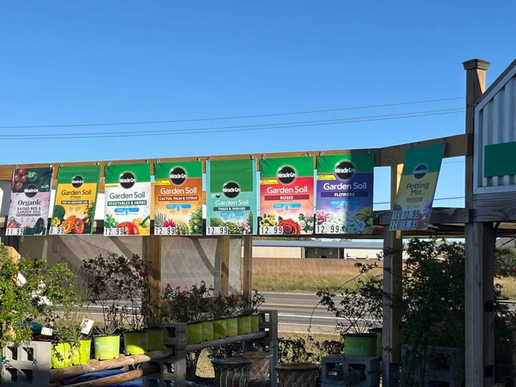 Custom outdoor garden center product banners installed above plant displays featuring full-color UV printed aluminum signs.