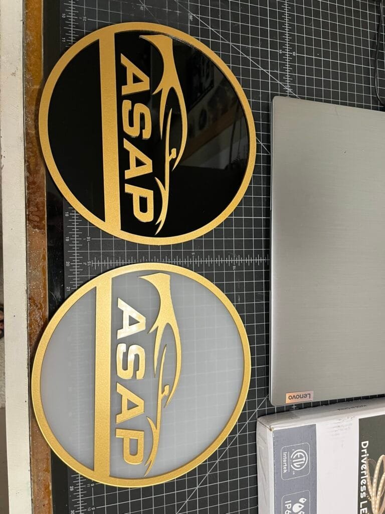 Custom layered acrylic business logo sign with gold lettering on black and frosted acrylic backgrounds, precision cut by CNC and laser.